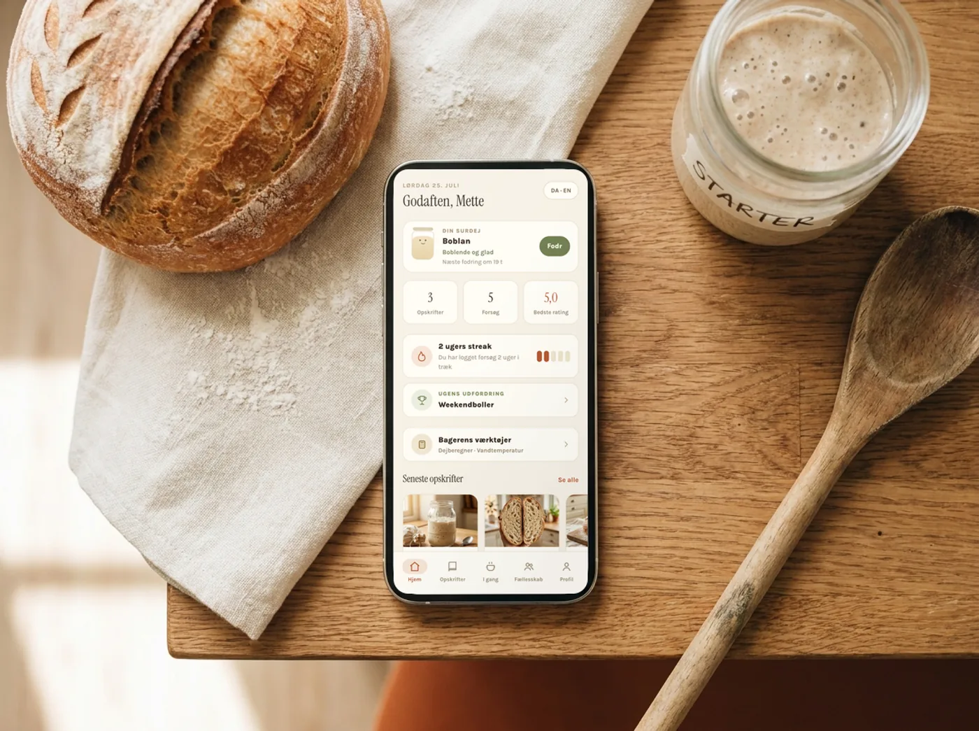 MyHappyDough åben på en telefon ved siden af et nybagt surdejsbrød